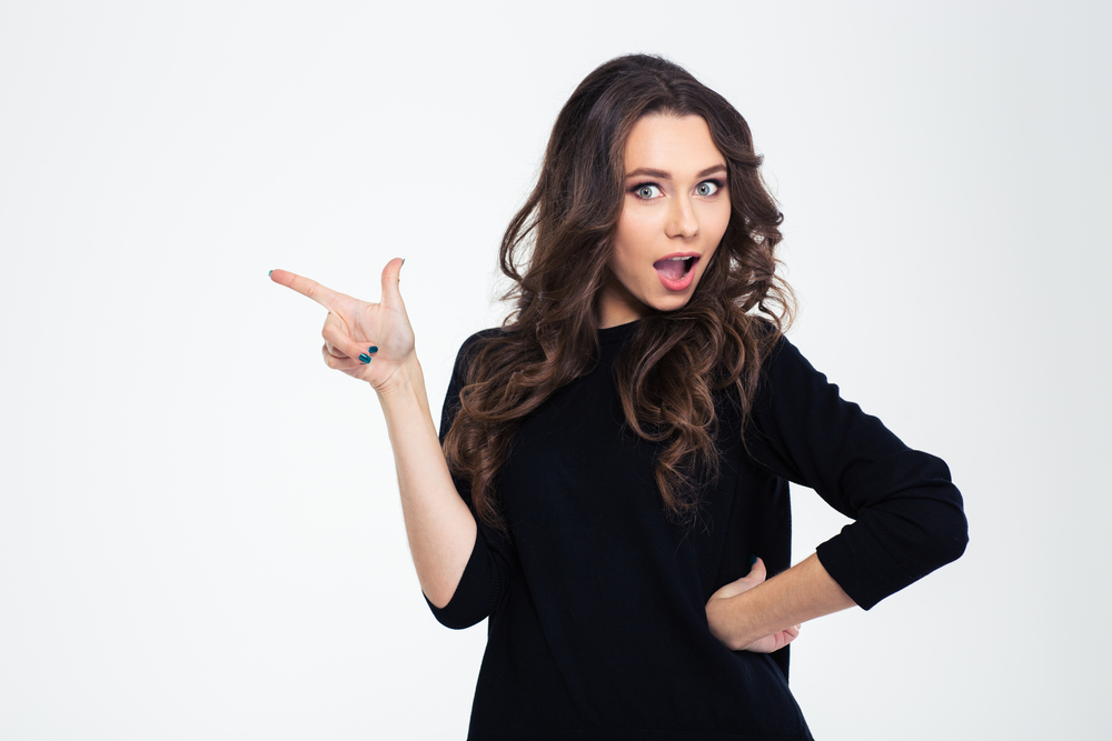 Portrait of a beautiful woman pointing finger away isolated on a white background