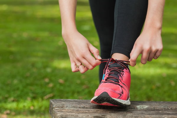 Young woman tying the shoelaces of her running shoes on a bench